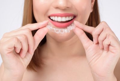 Young,Smiling,Woman,Holding,Invisalign,Braces,In,Studio,,Dental,Healthcare